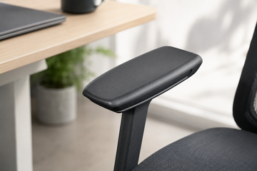 Person sitting in an ergonomic chair with properly adjusted armrests supporting their forearms at desk