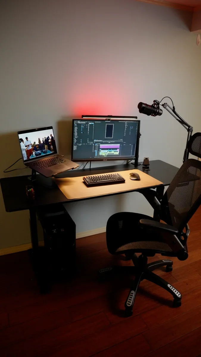 OdinLake standing desk with monitor, laptop, microphone, and computer cables routed behind the workspace