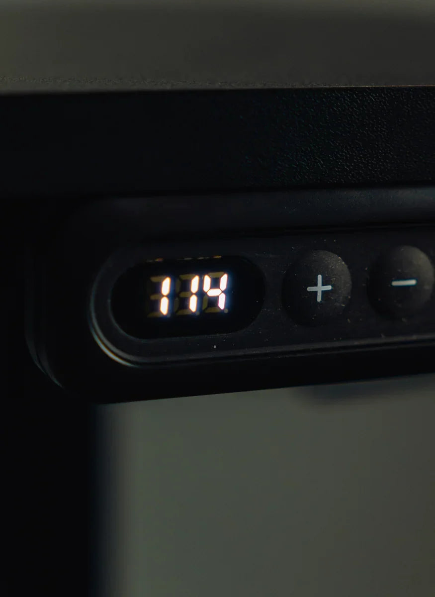 Close view of an illuminated standing desk height display and adjustment buttons